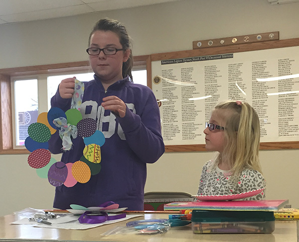 Allison Britton and Brooklyn Larson give a demonstration on “How to Make a Paper Easter Egg Wreath”