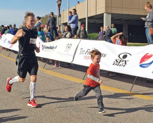 JEFF SCHULZ runs the favorite part of his race, final stretch across the finish line with his son, Jobe, Sunday morning at the Mankato Marathon.